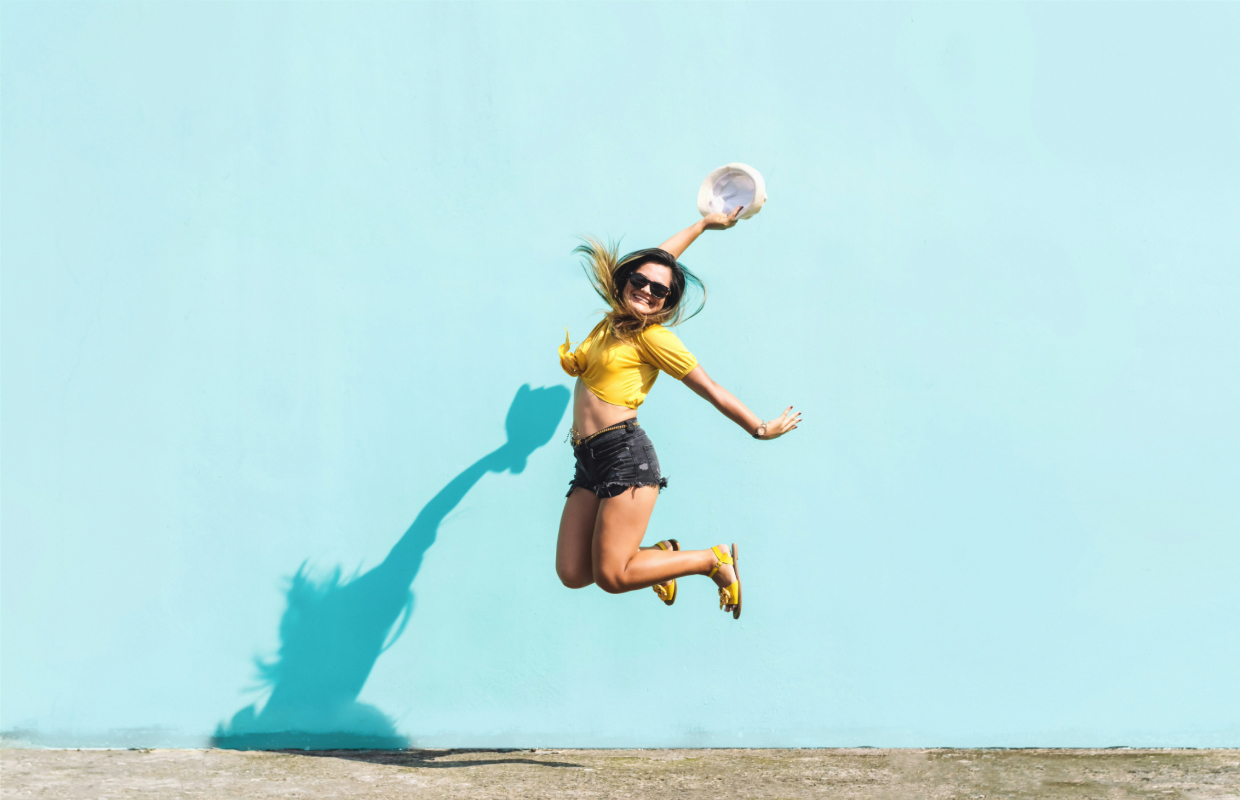 A girl jumping in front of blue wall 