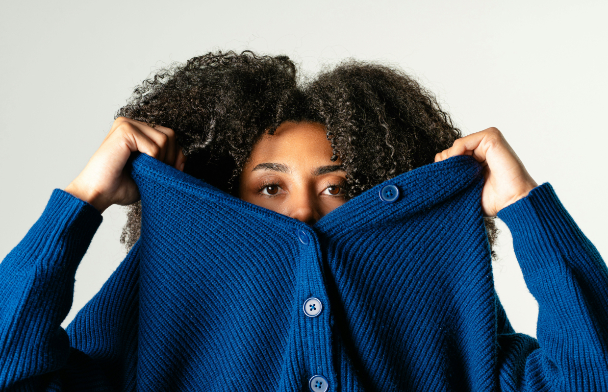 Woman pulling a blue jumper over her face