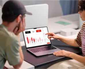 Two people looking at a laptop with stats