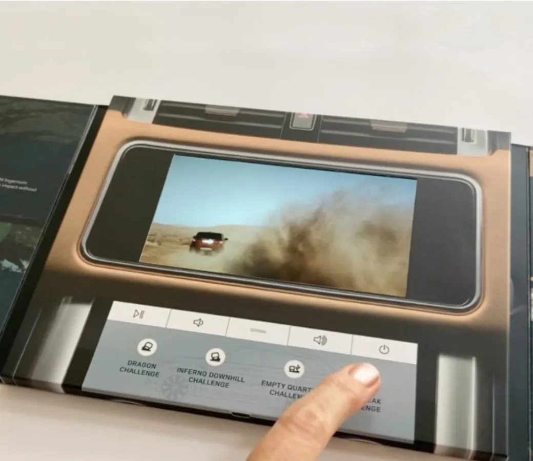 A Land Rover video brochure with built-in screen, showing off-road footage and interactive buttons for challenges